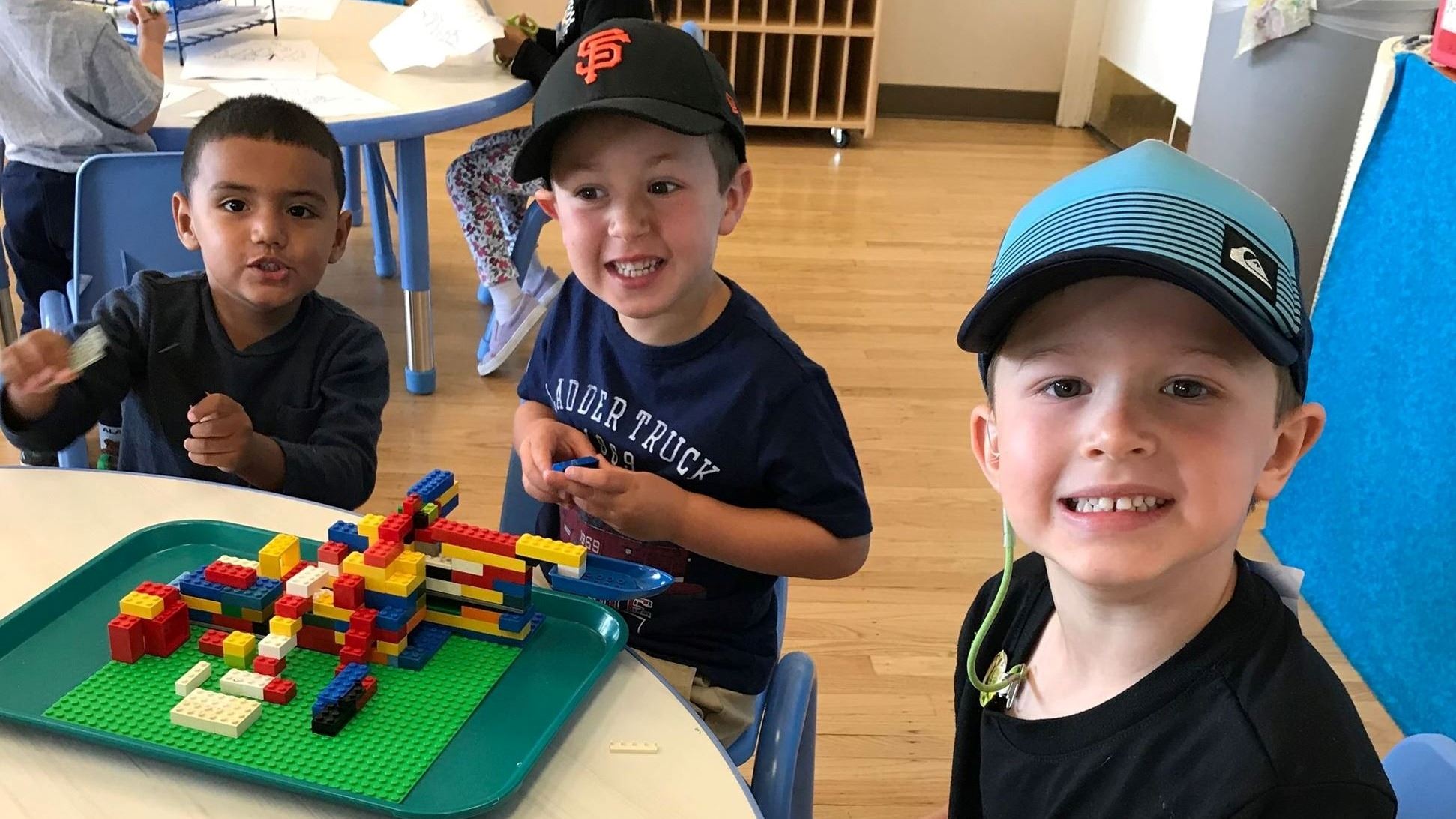 Photo of preschool students playing at a table.