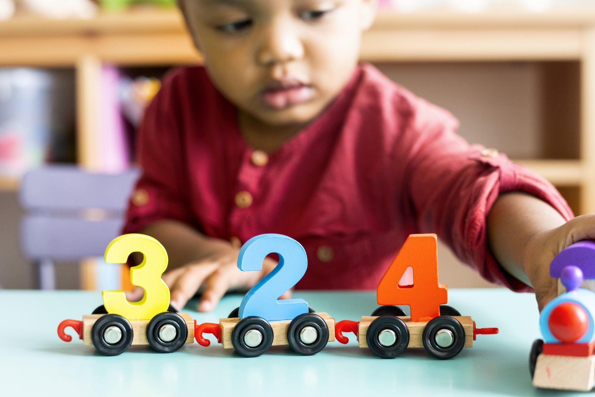 African American toddler playing with a number train on the table
